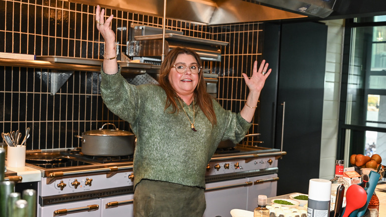 Rachael Ray in a kitchen throwing her hands into the air in exasperation