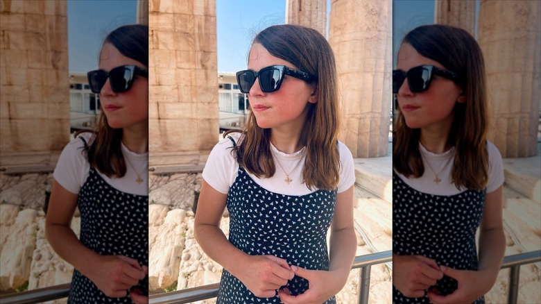 Raegan Revord looks off to the left in front of Greek ruins.