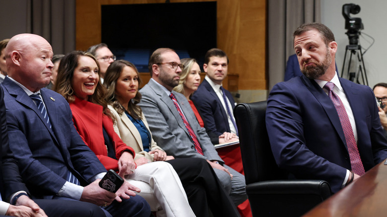 Markwayne Mullin smirking at people seated behind him