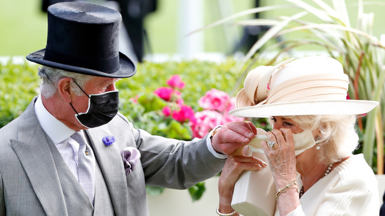 King Charles helping Queen Camilla with face mask