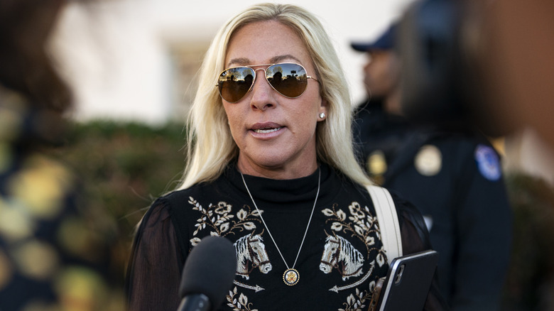 Marjorie Taylor Greene wearing sunglasses while speaking to the media