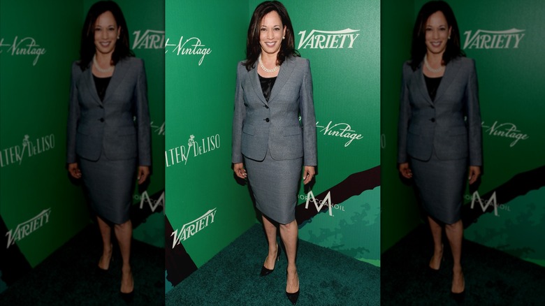 Kamala Harris smiling and standing in front of green backdrop