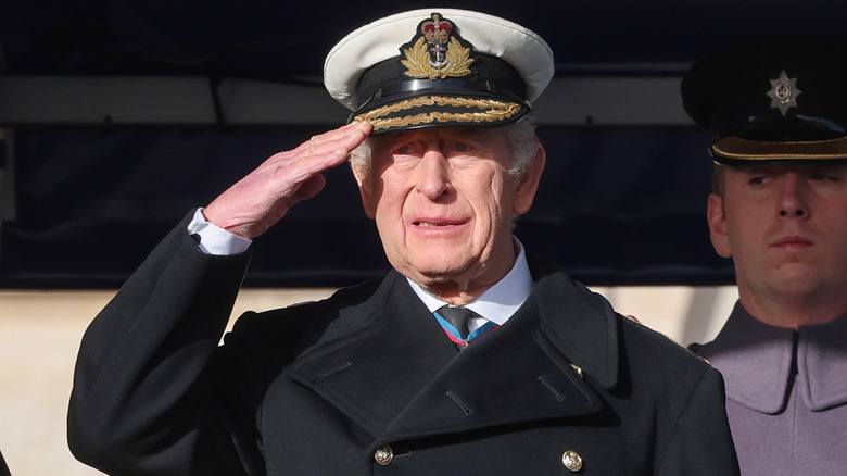 King Charles III wearing a military cap and saluting