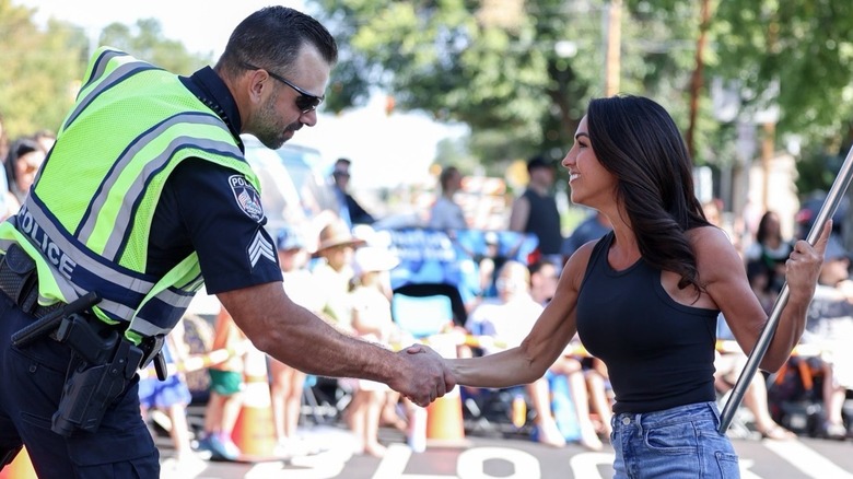 Lauren Boebert shakes the hand of a police officer while holding a flag