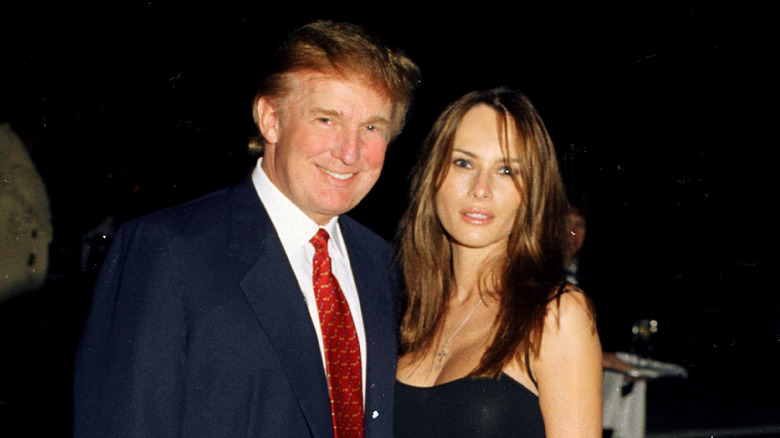 Donald Trump smiling with his arm around a nonsmiling Melania Trump