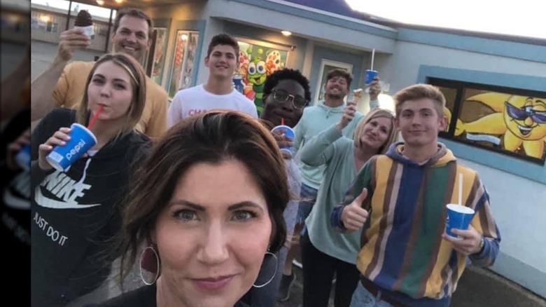 Kristi Noem making a wry expression with people smiling behind her