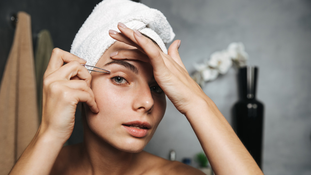woman tweezing brows
