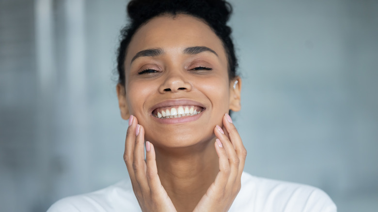 Smiling woman touching her face