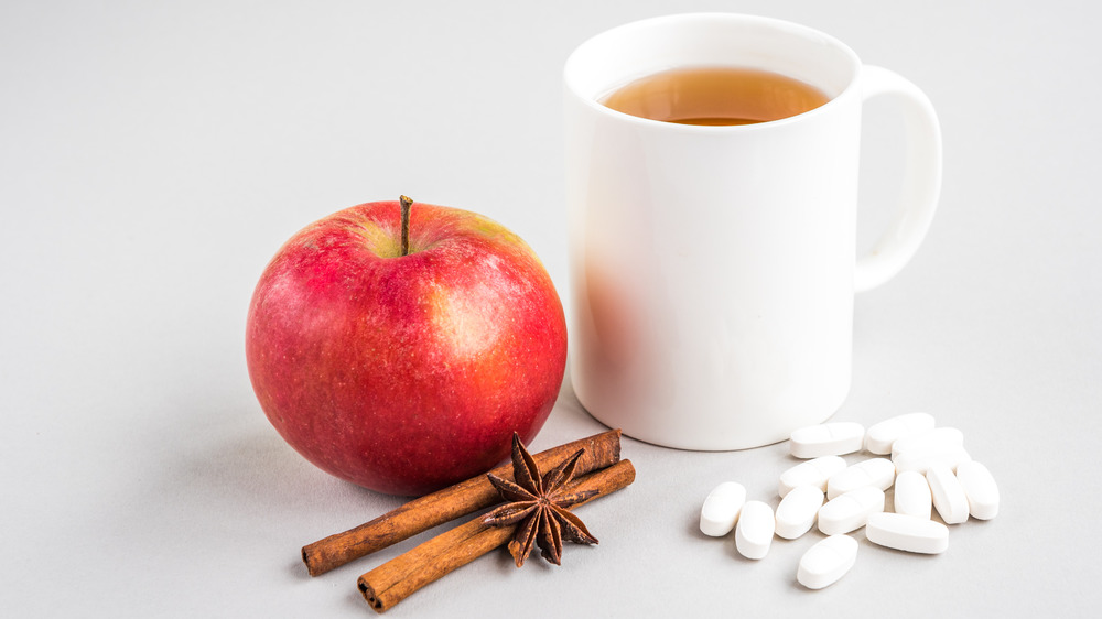 Apple, white pills, cinnamon sticks, mug