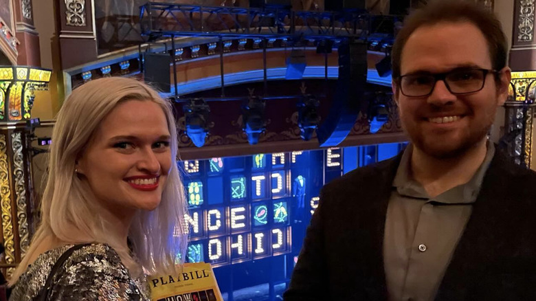 Tom McGowan's two children, Mark and Mary, smile standing next to each other in a theater while Mary holds a Playbill