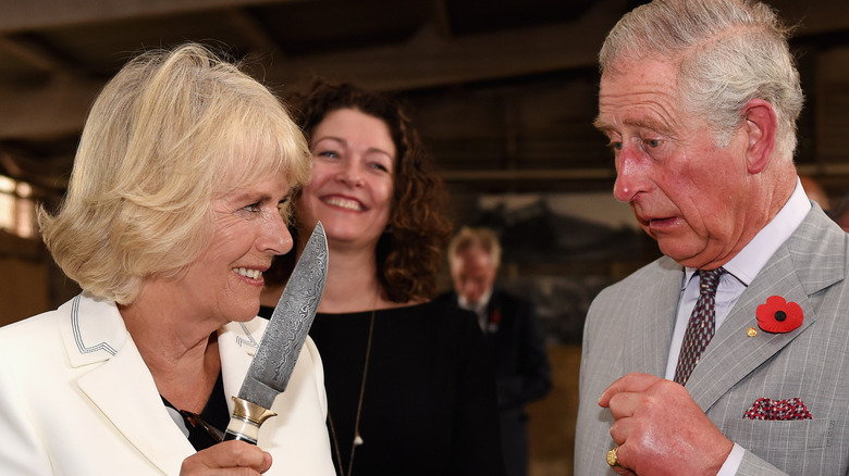 Queen Camilla holding knife to King Charles