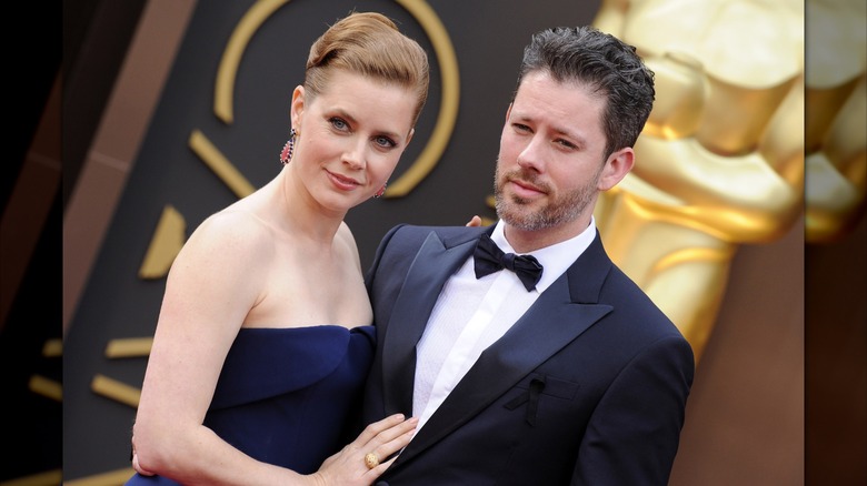 Amy Adams placing her hand on Darren Le Gallo's chest in front of an Oscar statue.