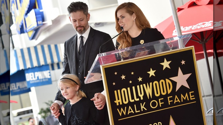 Darren Le Gallo holding his daughter Aviana's hands while Amy Adams speaks at her Hollywood Walk of Fame induction ceremony.