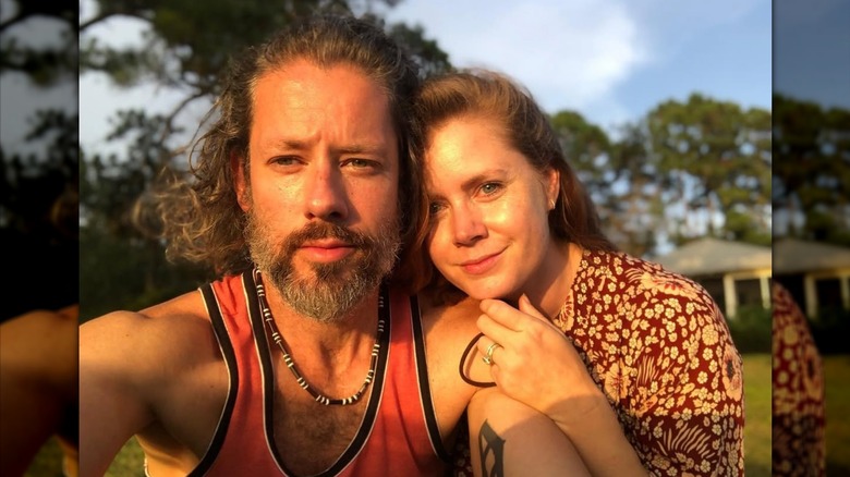 Amy Adams placing her hand and chin on Darren Le Gallo's shoulder outdoors.