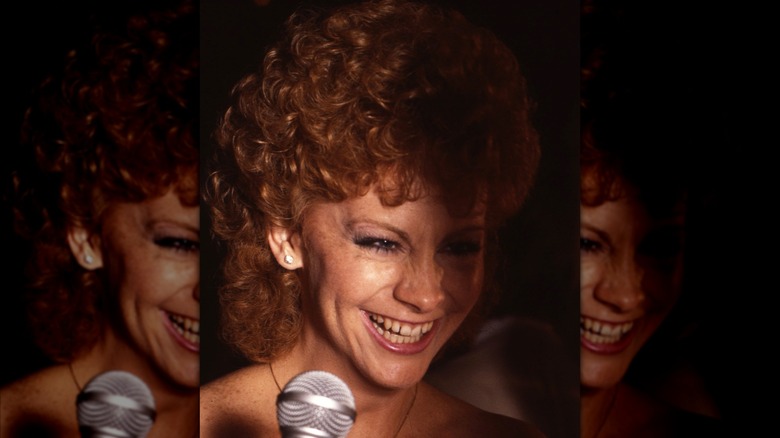 Reba McEntire smiling in front of microphone