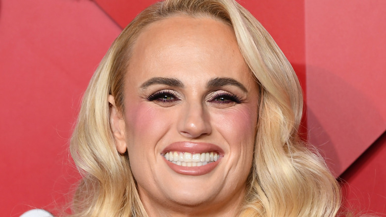 Rebel Wilson displays flowing blond locks, a wide peachy smile, and pearly whites on the red carpet