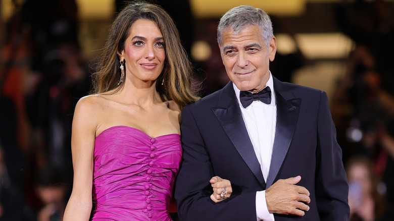 Amal Clooney and George Clooney walking arm-in-arm in formal wear