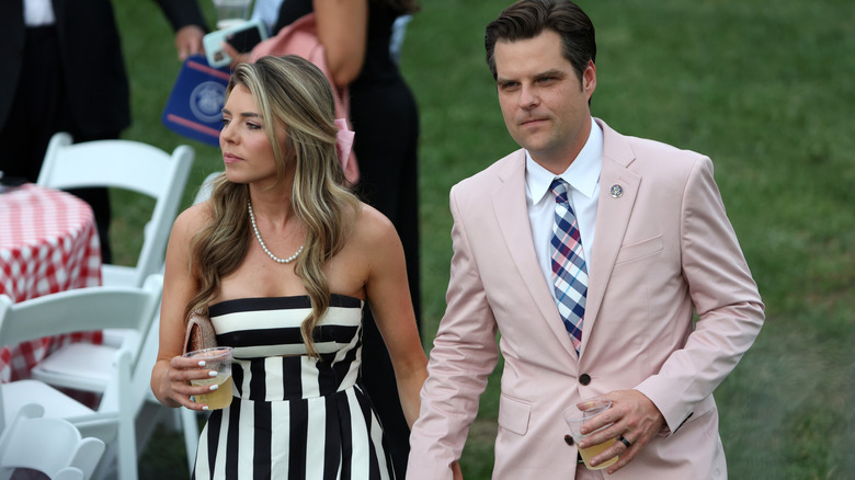 Matt Gaetz in a pink suit holds Ginger Gaetz hand at the Congressional Picnic