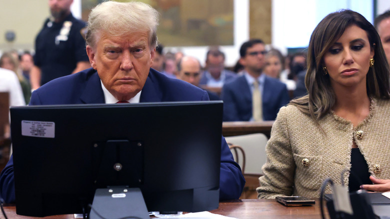 Alina Habba and Donald Trump looking serious while seated next to each other in court