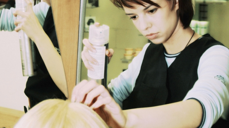 Nervous hairdresser with hairspray