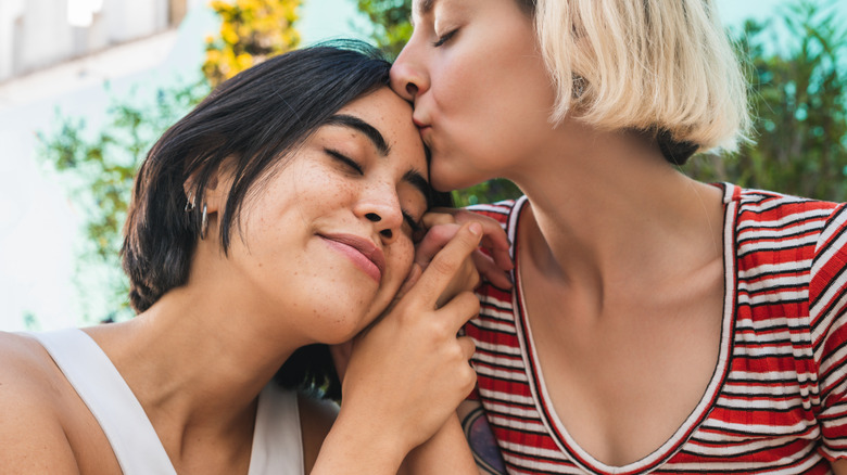 lesbian couple holding hands, kissing forehead
