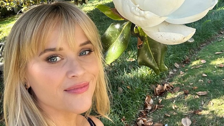 Reese Witherspoon with fresh bangs in a garden