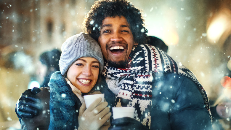 Multiracial couple snuggling in snow