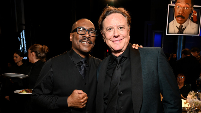 Eddie Murphy and Judge Reinhold smile while posing together at an event