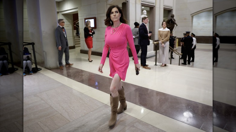 Nancy Mace in a bright pink dress walking the halls of the congressional building.