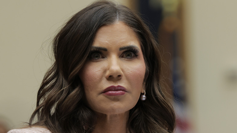 Kristi Noem looking grim in pink lipstick