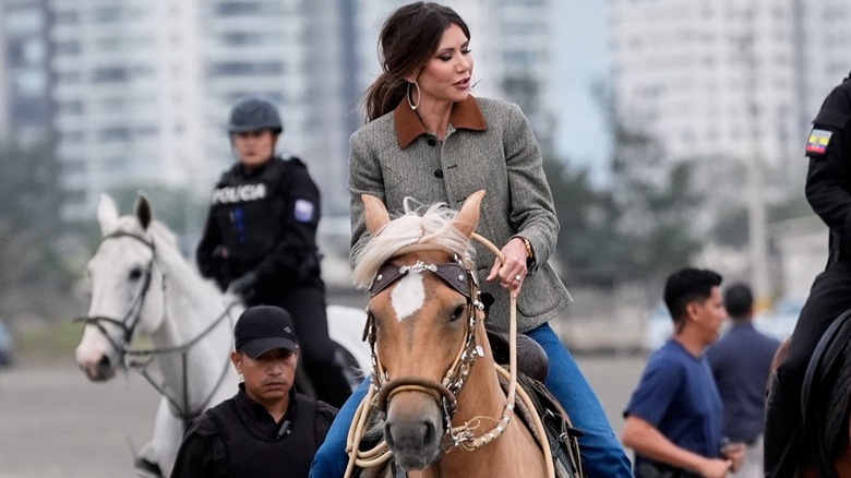 Kristi Noem riding a horse on a city street