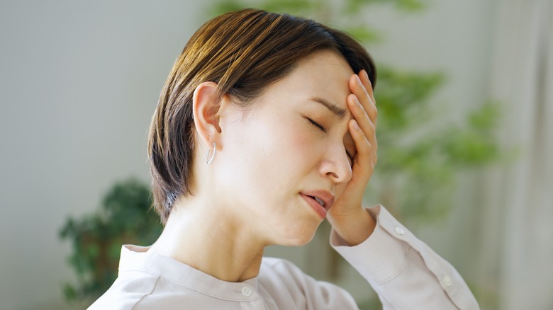 woman holding head in pain