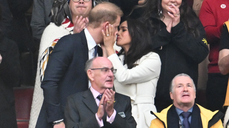 Prince Harry and Meghan Markle kissing during the opening ceremony of the 2025 Invictus Games