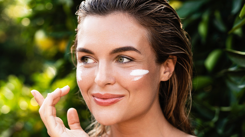 Woman applying sunscreen outside