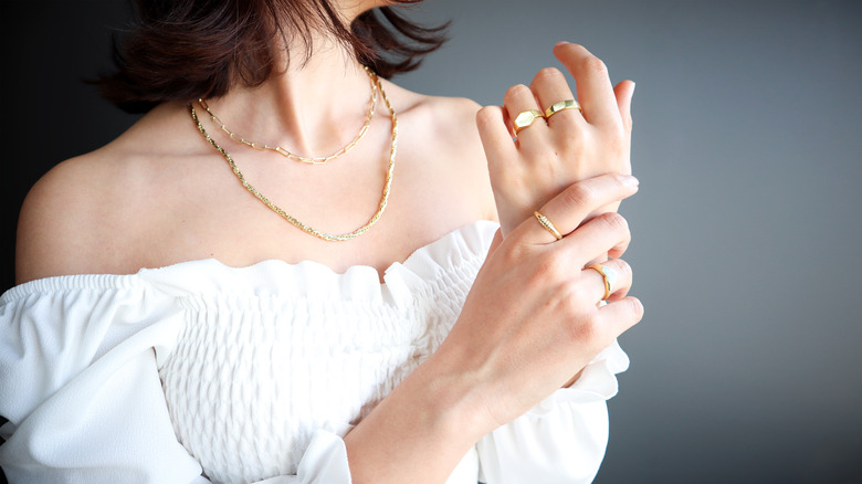 A woman shows off gold rings on both hands