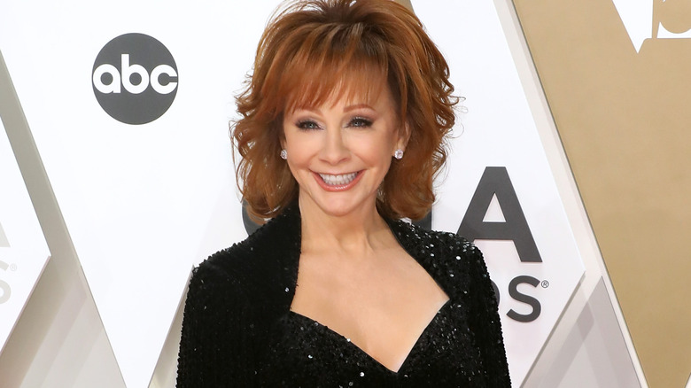 Reba McEntire smiling wearing black sparkly gown