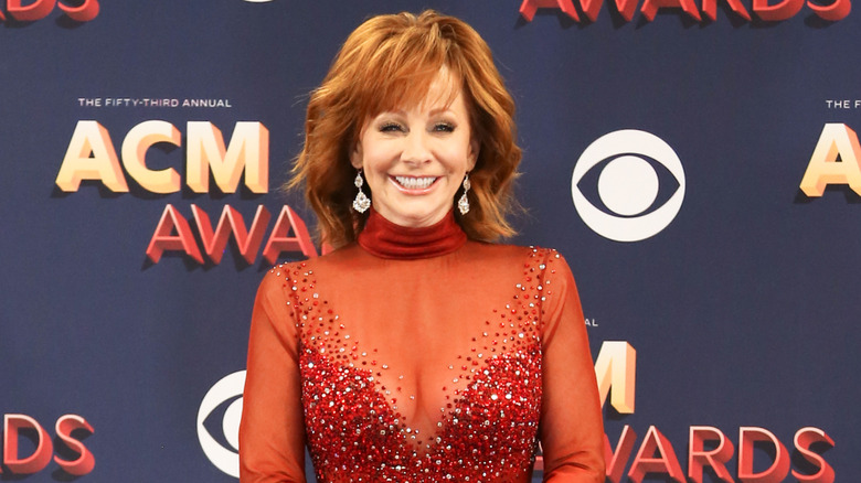 Reba McEntire smiling wearing red sparkly gown