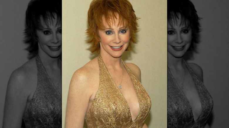 Reba McEntire smiling wearing low-cut champagne gown