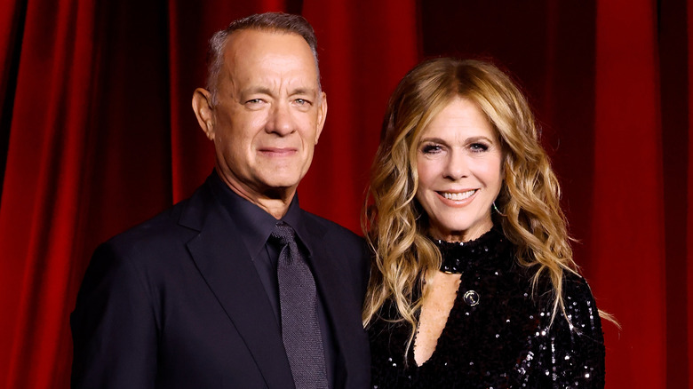 Rita Wilson and Tom Hanks smiling while posing together at a red carpet event