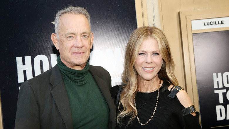Rita Wilson and Tom Hanks smiling while posing together at a red carpet event