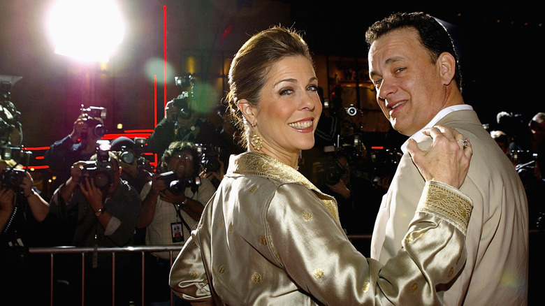 Rita Wilson and Tom Hanks looking over their shoulders and smiling before a crowd of photographers in March 2004