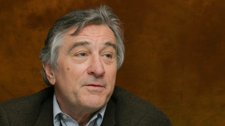 Robert De Niro clean-shaven against brown background