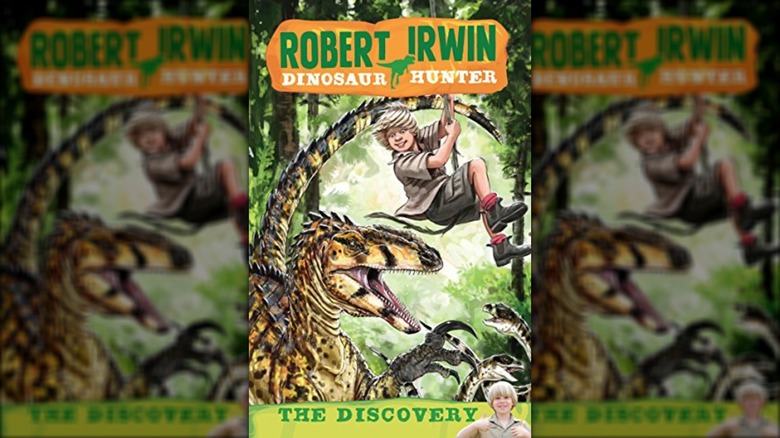 The cover for Robert Irwin: Dinosaur Hunter -- The Discovery, featuring an illustrated Robert Irwin swinging on a vine over a dinosaur