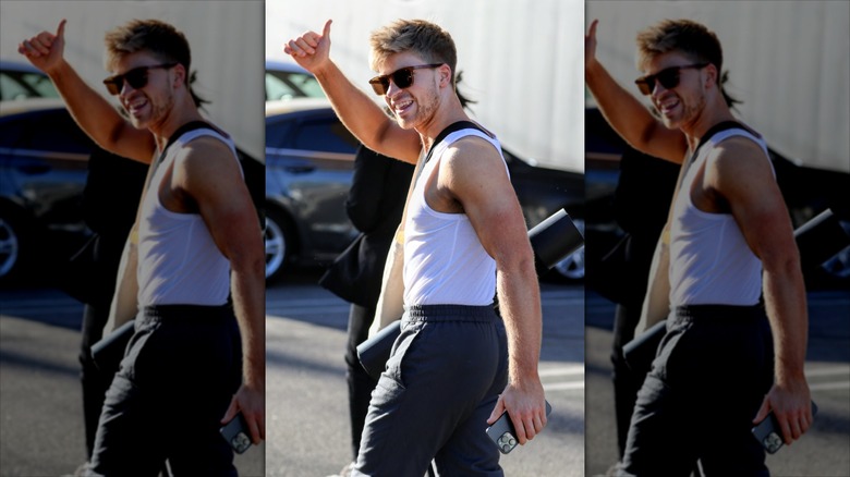 Robert Irwin in sunglasses and a white tank-top flashes a thumbs-up to the camera