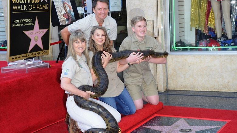 Terri, Bindi, and Robert Irwin holding a giant python overtop of their dad's Walk of Fame star