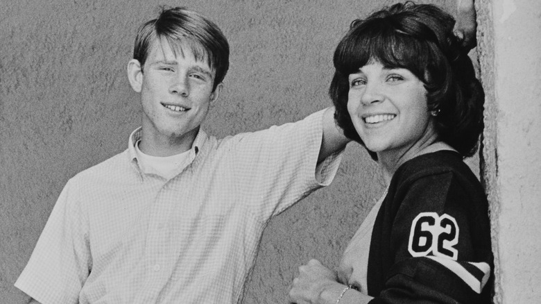 Ron Howard and Cindy Williams smiling while posing on the set of 'American Graffiti'