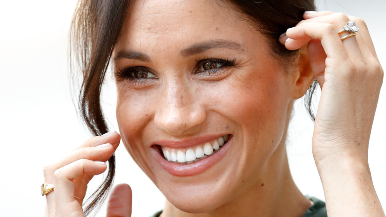 Meghan Markle puts hands up to smiling face