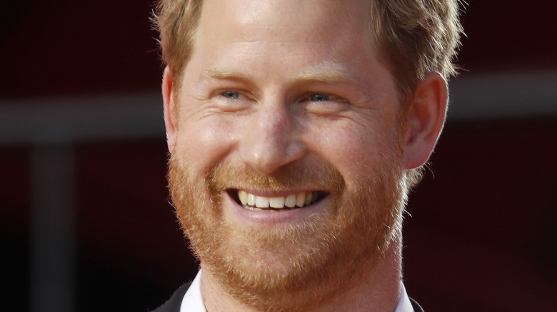 Prince Harry smiling onstage with a microphone