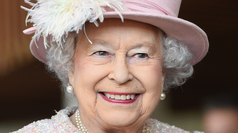 queen elizabeth smiling in a pink hat