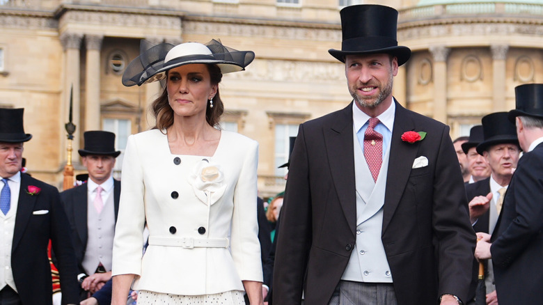 Princess Catherine and Prince William holding hands while posing in their finery